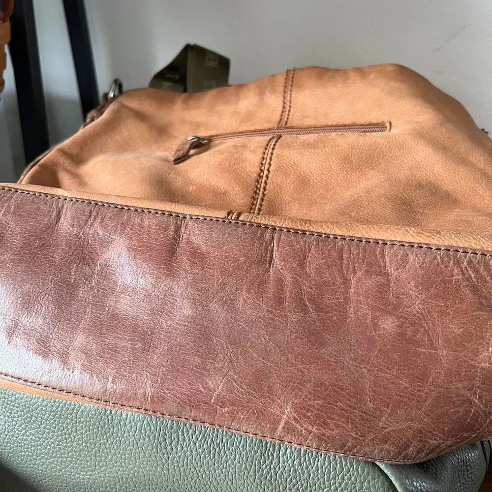 Tan leather shoulder bag with zipper closure, multiple pockets & braided tassel